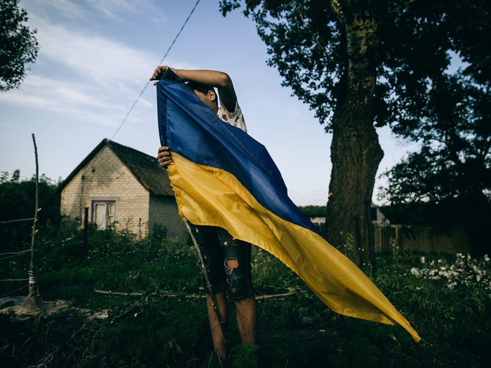 Mann auf dem Land mit ukrainischer Flagge