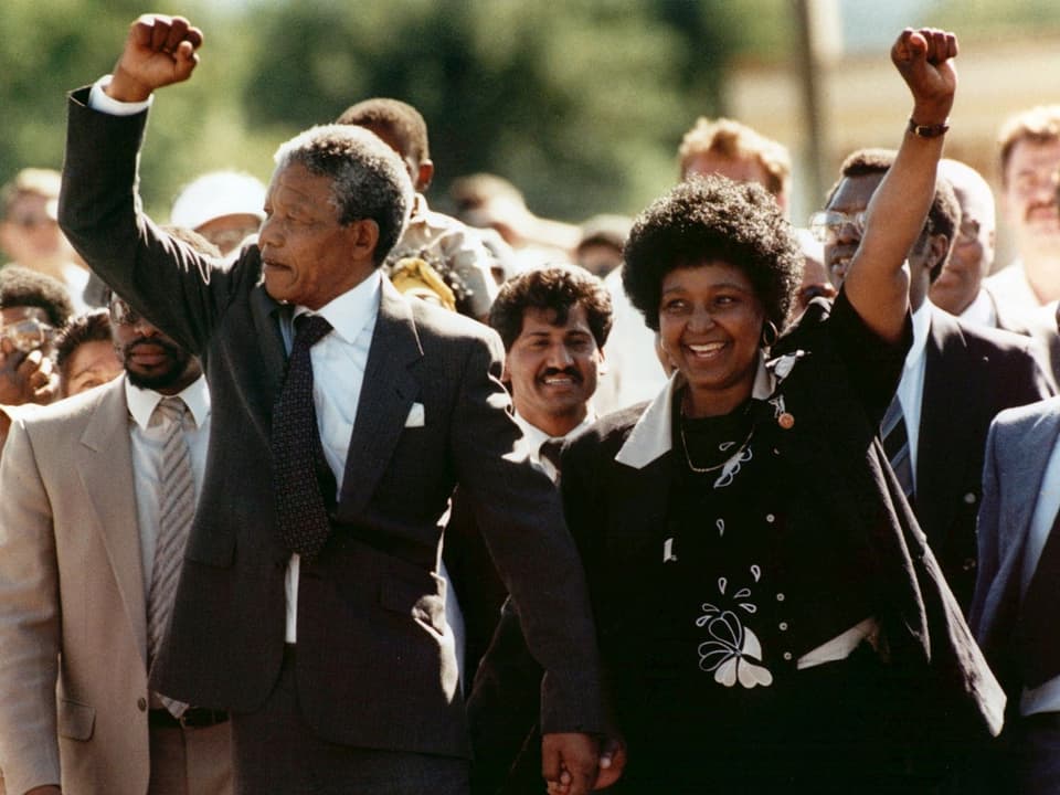 Nelson Mandela nach seiner Freilassung, Hand in Hand mit seiner damaligen Frau Winnie, beide halten eine Faust in die Höhe.