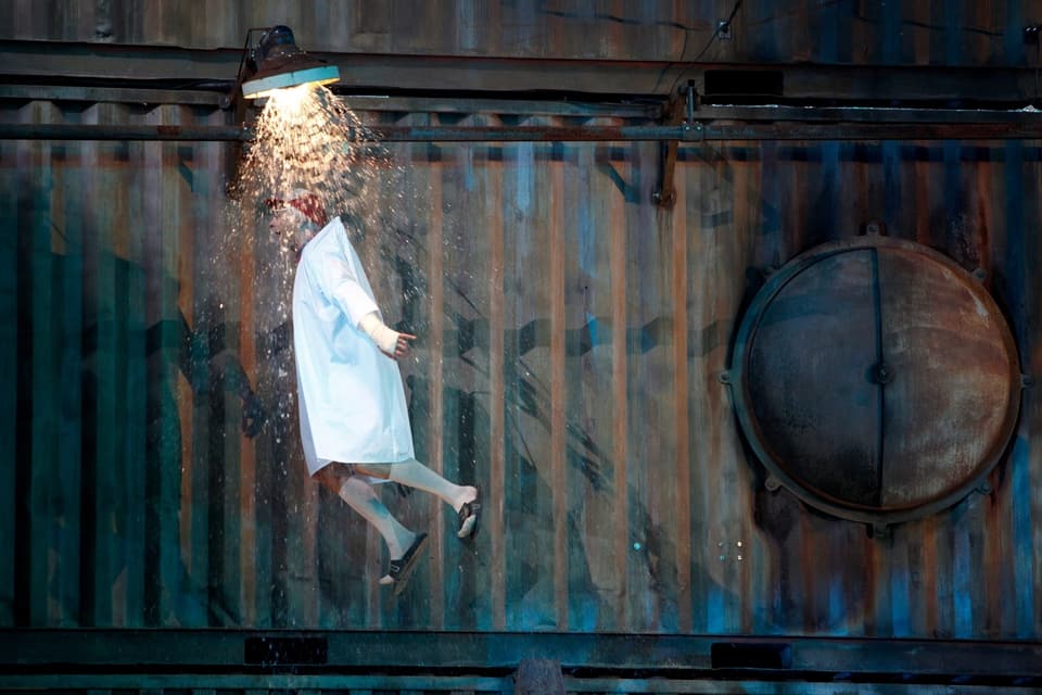 Ein Schauspieler fliegt durch den Raum, oberhalb seines Kopfes sprühen Funken aus einer Lampe.