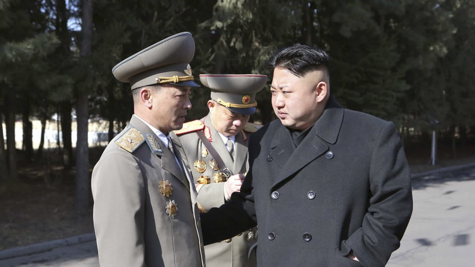 Kim Jong Un steht neben zwei Offizieren.