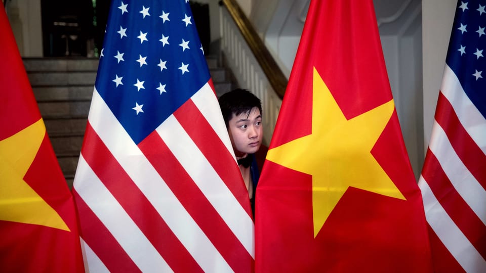 Ein Vietnamese steht zwischen der amerikanischen und der vietnamesischen Flagge.