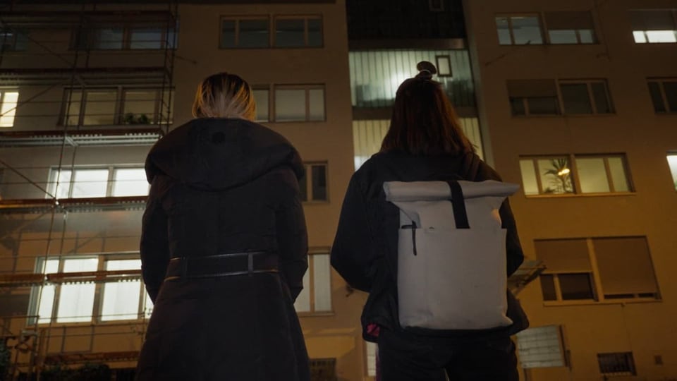 Zwei Frauen stehen vor einem Haus.