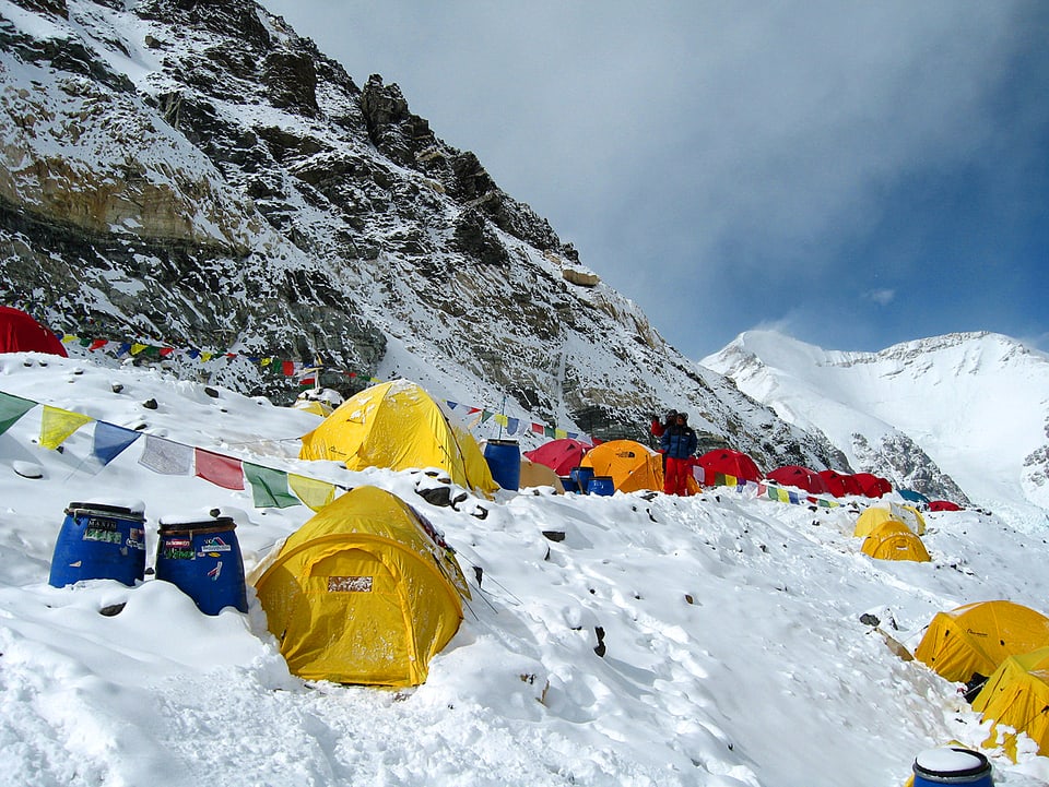Mehrere kleine bunte Zelte stehen in einem Eisfeld am Mount Everest.
