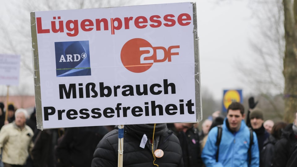 Demonstrant hält ein Schild hoch, auf dem steht: Lügenpresse ARD / ZDF, Missbrauch der Pressefreiheit.