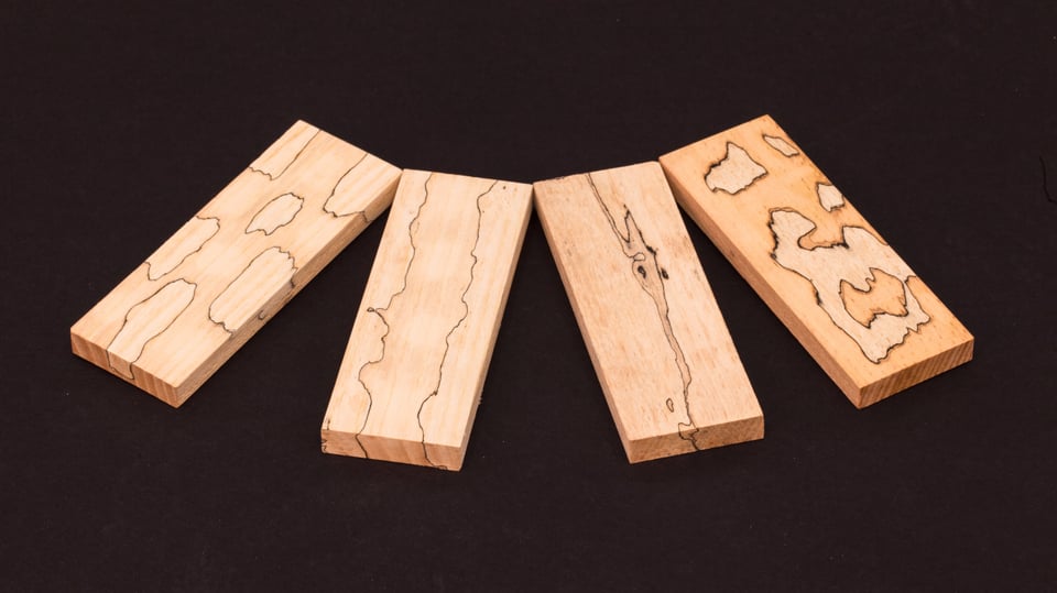 Vier Holzstücke mit unterschiedlichen Strukturen.