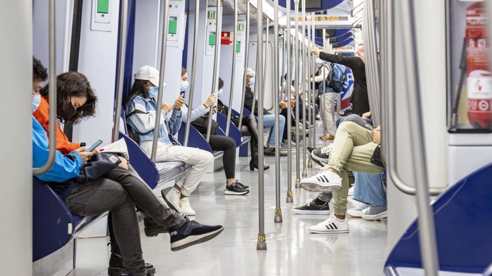 Menschen sitzen in einer Bahn in Madrid.