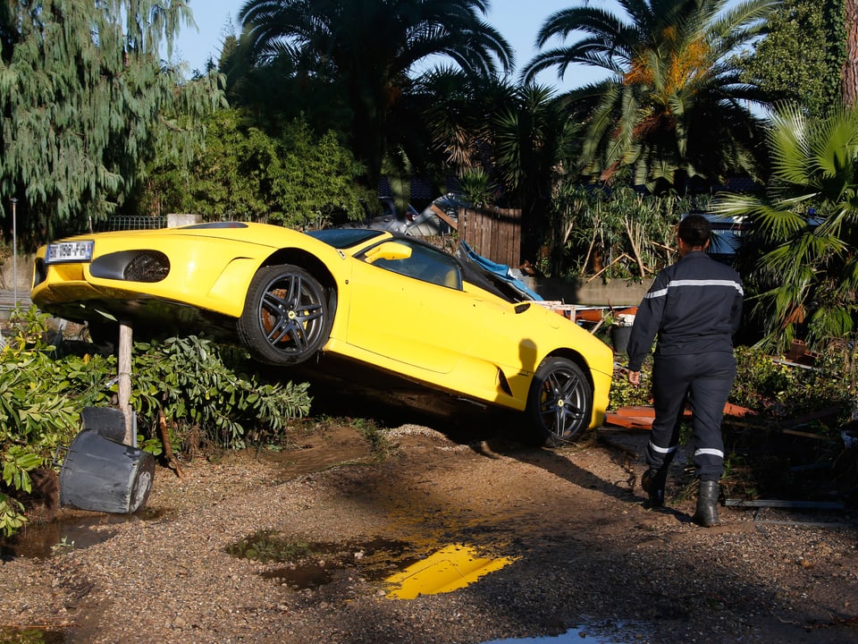 Ein Feuerwehrmann geht an einem zerstörten Ferrari vorbei.