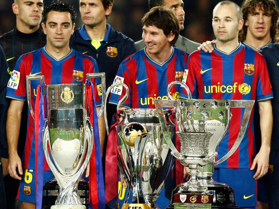 Iniesta steht mit Messi und Xavi vor den 6 gewonnenen Pokalen.