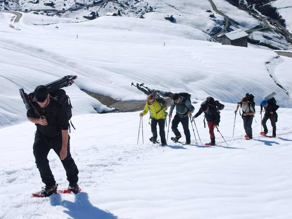 TV-Team stapft mit Schneeschuhen durch die verschneite Berglandschaft. 