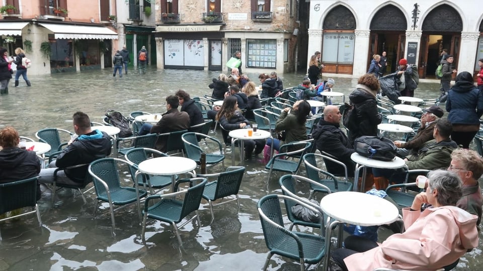 Menschen in Cafes trotz Hochwasser.