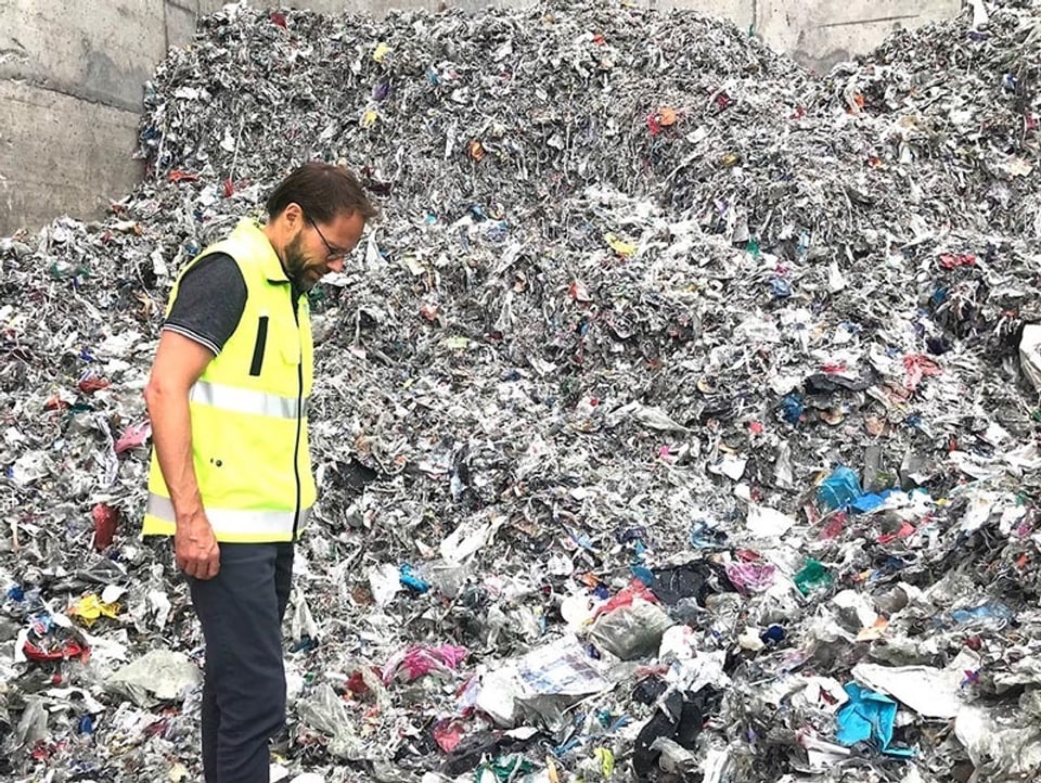 Mitarbeiter der Papierfabrik Perlen steht vor einem Berg Kunststoffabfall