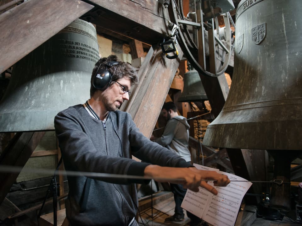Musiker im Glockenturm mit Kopfhörer und Noten.