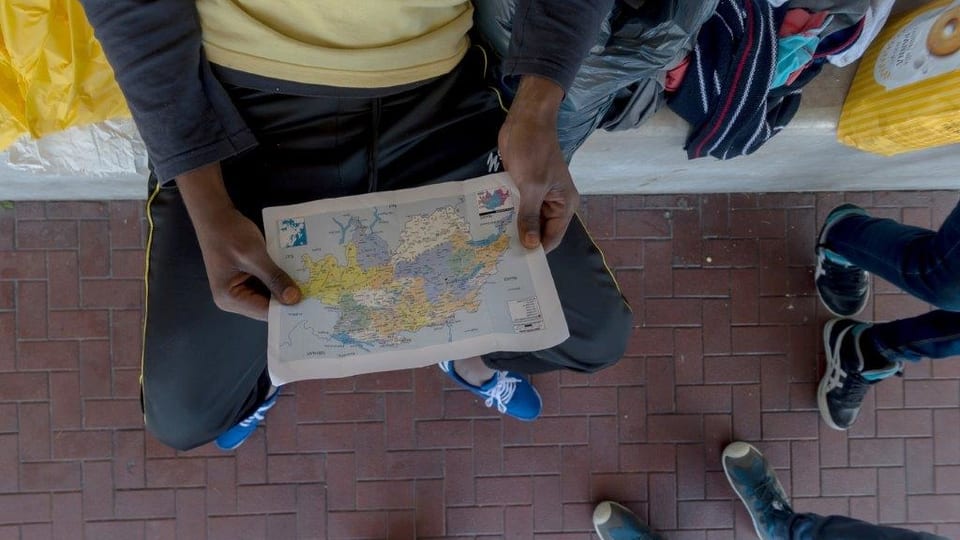 Ein Flüchtling schaut sich eine Schweizer Karte an.