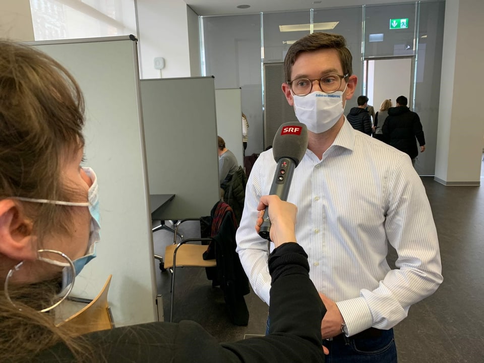 Reporterin interviewt Mann mit Schutzmaske.