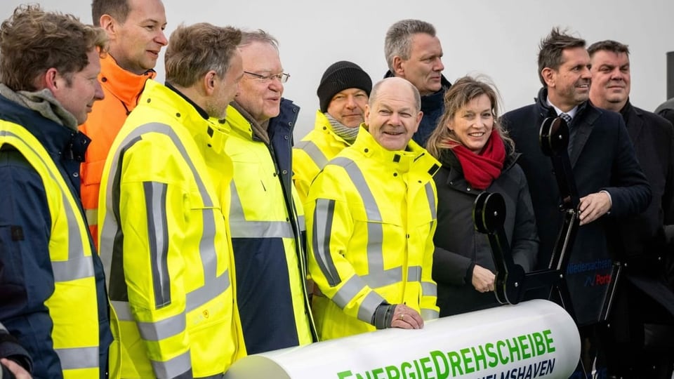Olaf Scholz (Mitte) bei der Einweihung des LNG-Terminals an der Nordsee. Er trägt eine gelbe Signaljacke.