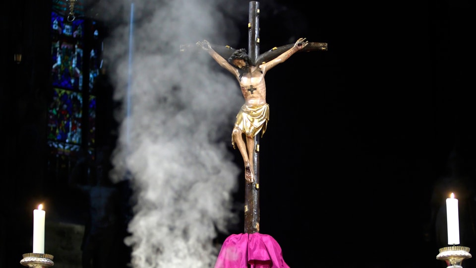 Jesus-Kruzifix, aufsteigender Weihrauch und zwei brennende Kerzen