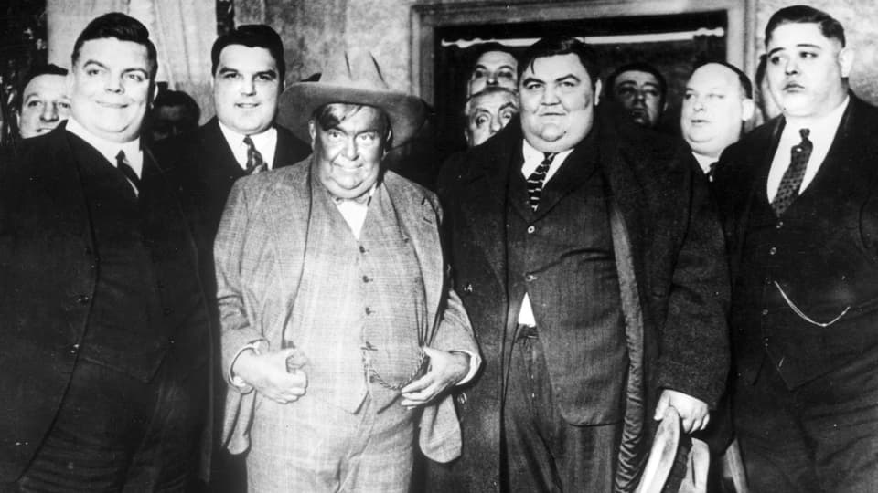 Übergewichtige Männer in Anzügen auf einem Schwarzweissbild aus den 1930er-Jahren.