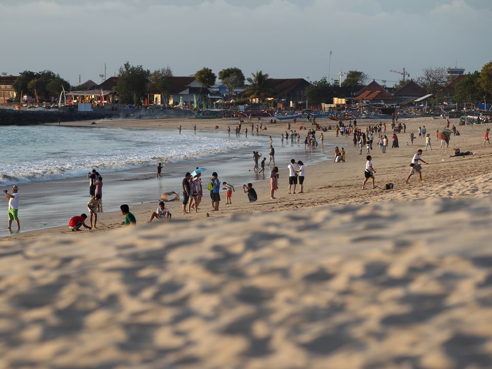 Menschen erholen sich am beliebten Jimbaran-Strand.