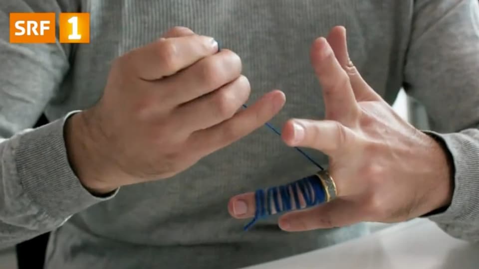 Ein Finger wird mit einer Schnur umwickelt, um den Ring zu entfernen. 
