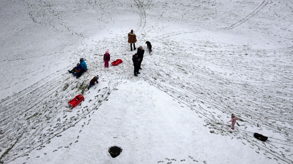 Kinder mit Schlitten und Rodelgefährten auf einer dünnen Schneeunterlage in Bern 
