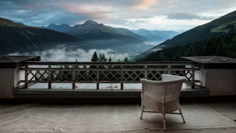 Ausblick vom Berghotel Ein Stuhl auf einer Terrasse, schöner Ausblick in das Tal mit Nebelschwaden