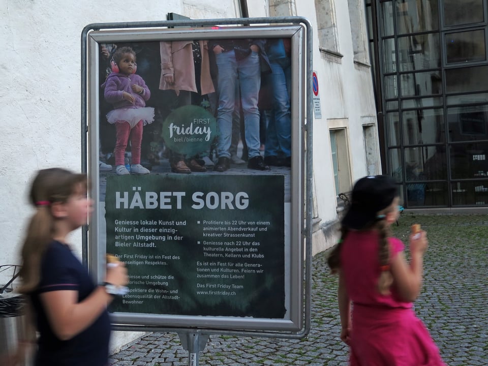 Zwei Mädchen vor einem Plakat mit Aufschrift Häbet Sorg