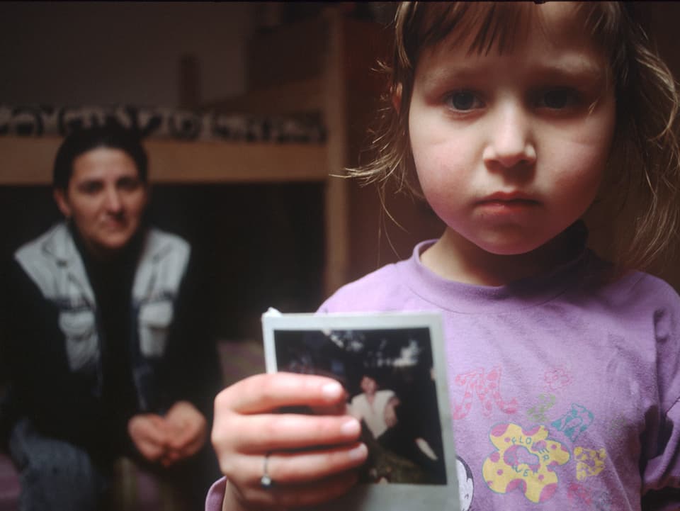 Ein Mädchen aus dem Kosovo mit dem Bild ihres vermissten Vaters. 