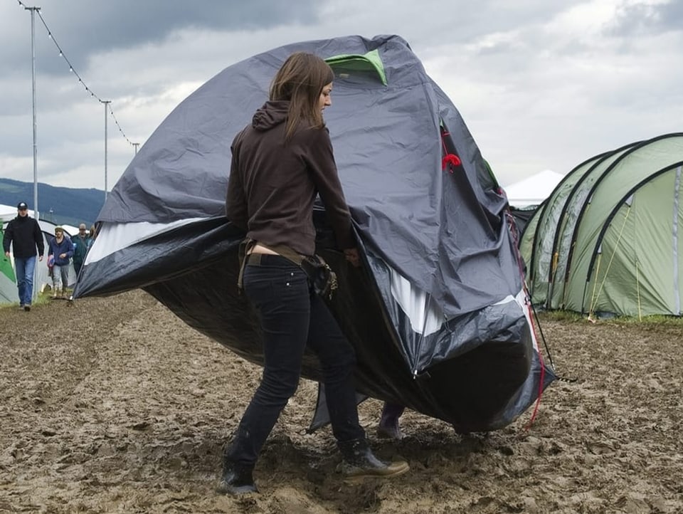 Eine Frau stellt ein Zelt im Schlamm auf. 