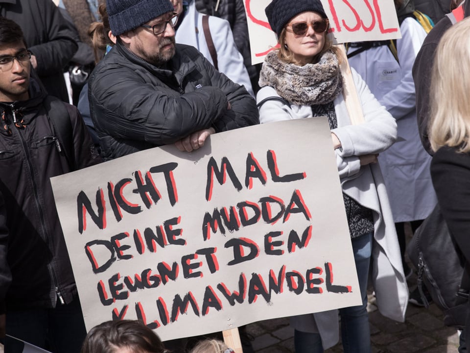Ein Mann hält ein Plakat, auf dem steht: «Nicht mal deine Mudda leugnet den Klimawandel.»