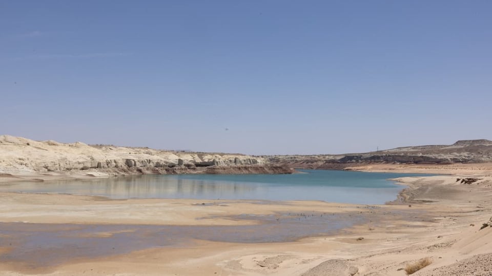 Eine wüstenartige Landschaft mit einer kleinen Wasserfläche im Hintergrund