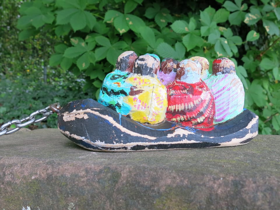 Kleines Schlauchboot mit farbigen Figuren drauf, die vermutlich Flüchtlinge darstellen