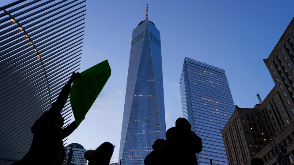 Protestierende Menschen stehen im Gegenlicht vor dem One World Trade Center.