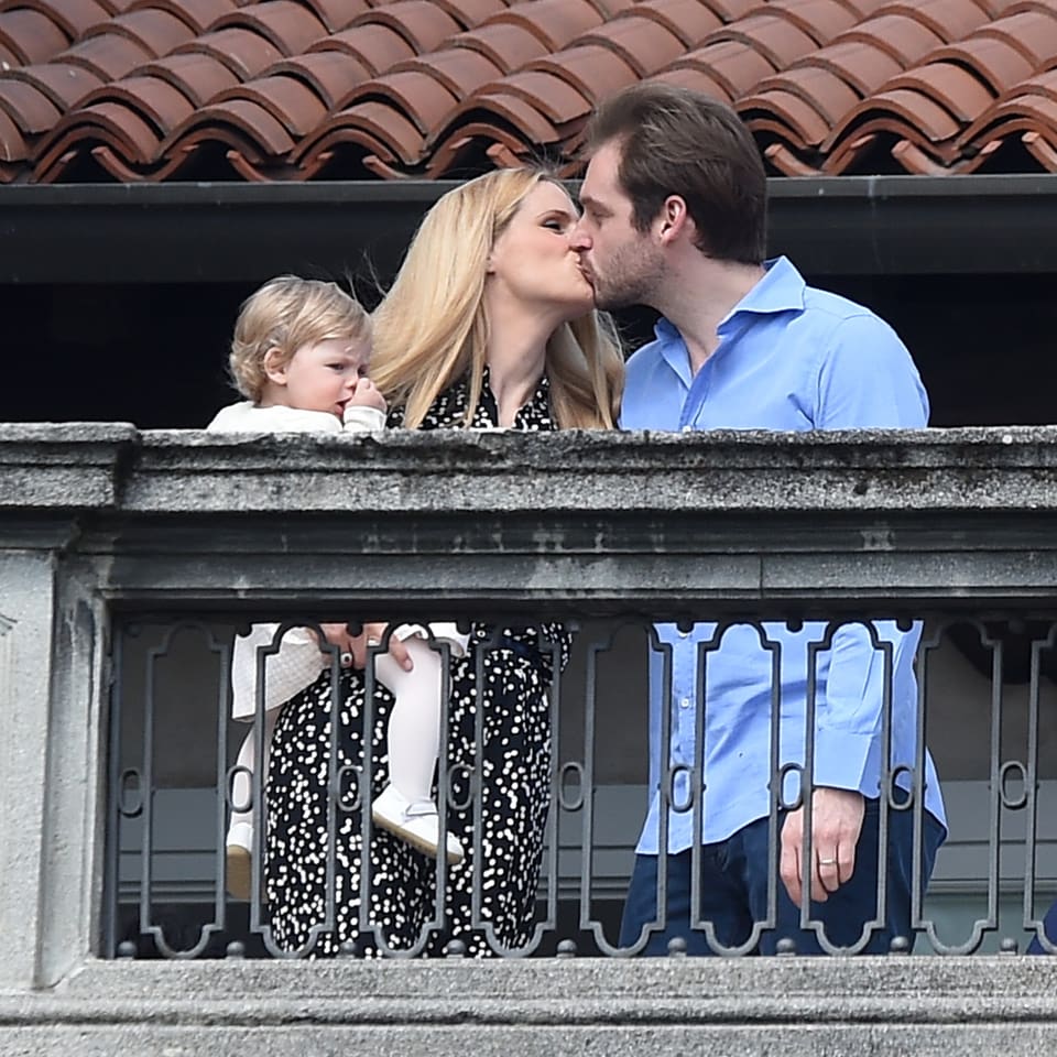 Blonde Frau küsst Mann, sie hat Baby auf Arm