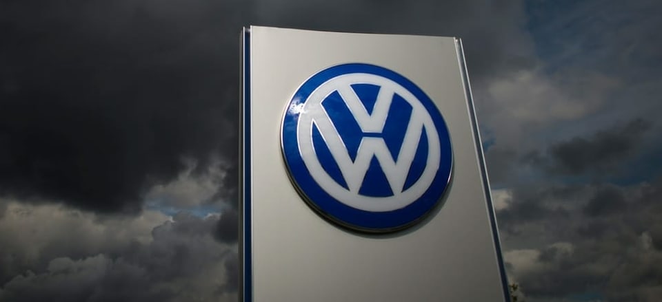 VW-Logo im Hintergrund dunkle Gewitterwolken