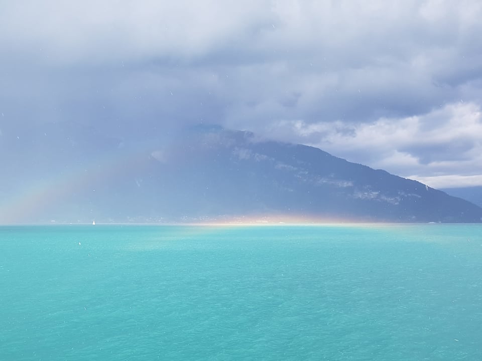 Blick von Spiez über den Thunersee mit Regenbogen.