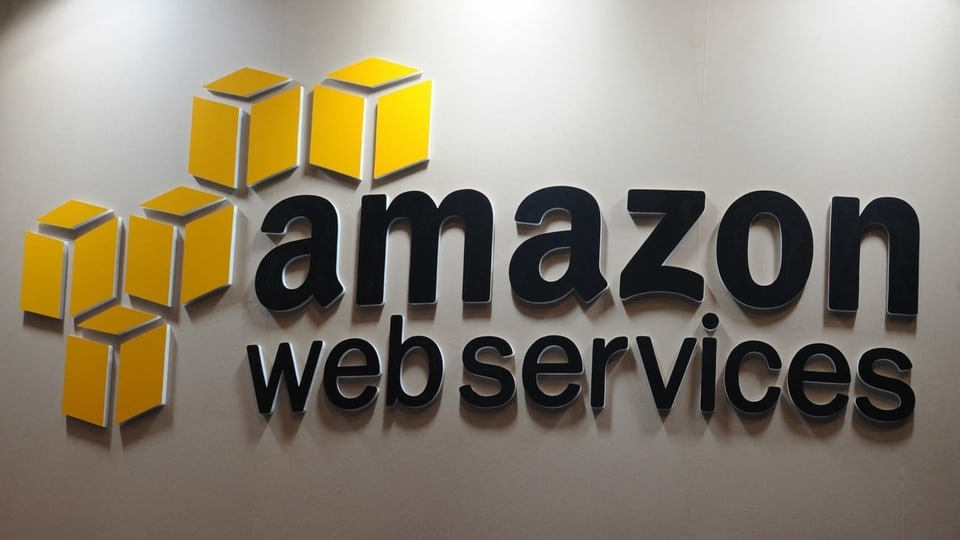 Das Logo von Amazon Web Services - schwarze Schrift, rechts fünf gelbe Würfel.