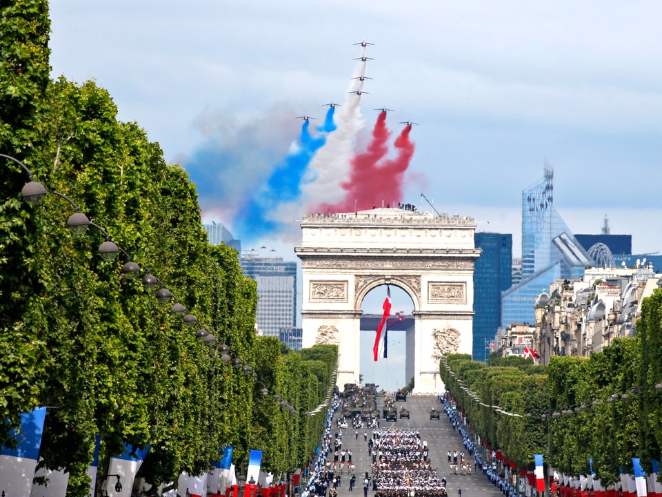 L'Arc de Triomphe mit Kampfjets, die farbige Rauchfahnen ablassen.