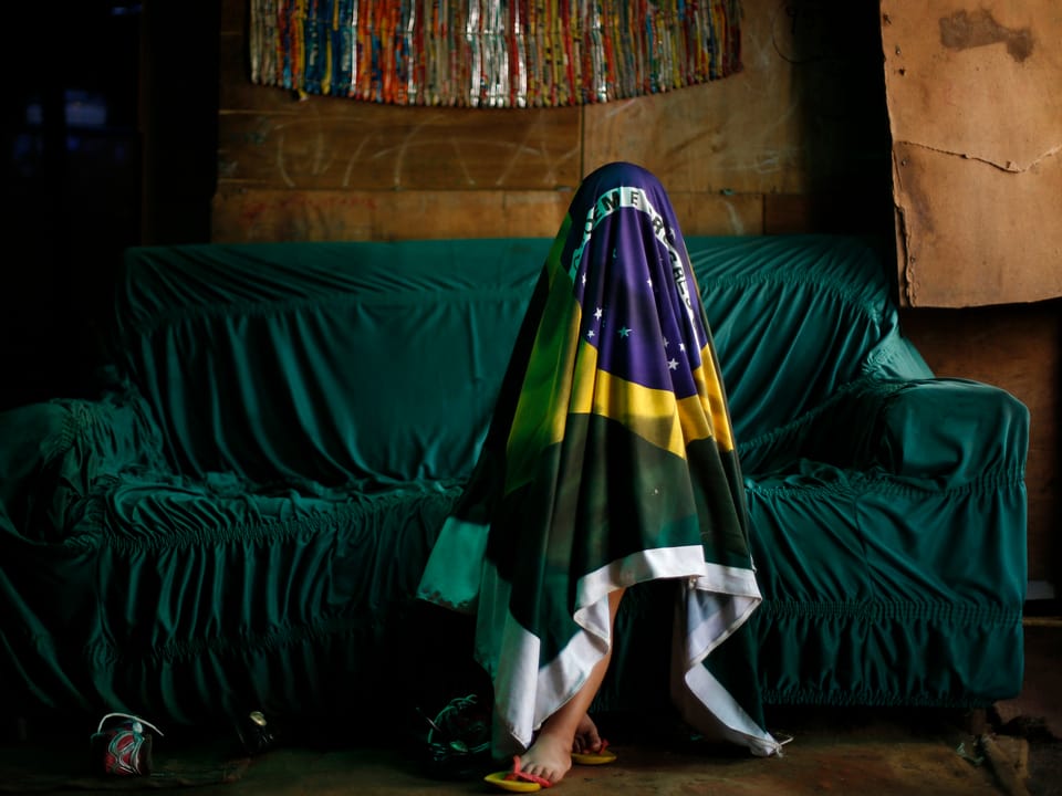 Mensch versteckt sich unter brasilianischer Flagge