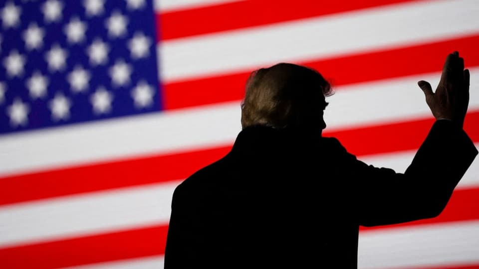 Trump von hinten vor einer grossen US-Flagge