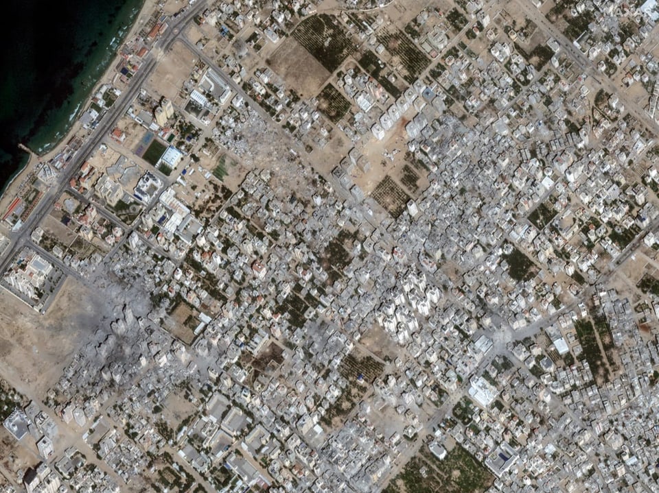 Satellitenaufnahme einer Stadt. Es sind zerstörte Quartiere und Gebäude zu erkennen.
