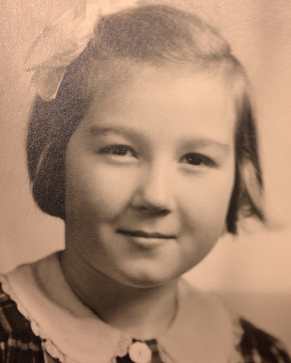 Nostalgische Fotografie eines kleinen Mädchens mit einer grossen Schleife in den Haaren.