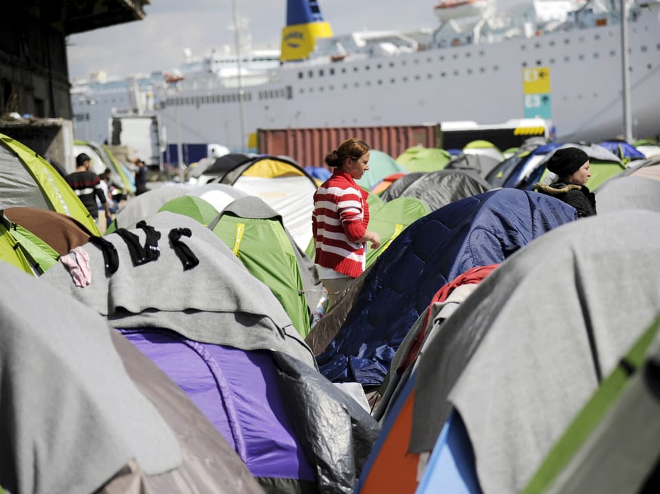 Am Hafen von Piräus stehen Dutzende Zelt. Dahinter hat ein grosses Passagierschiff angelegt. (reuters)