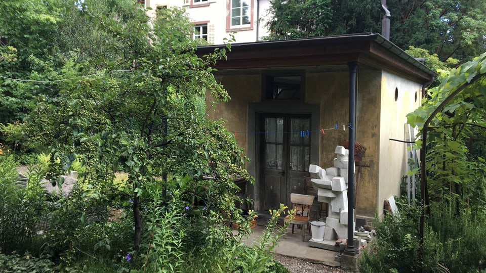 Blich durch einen Garten auf ein kleines Atelierhaus