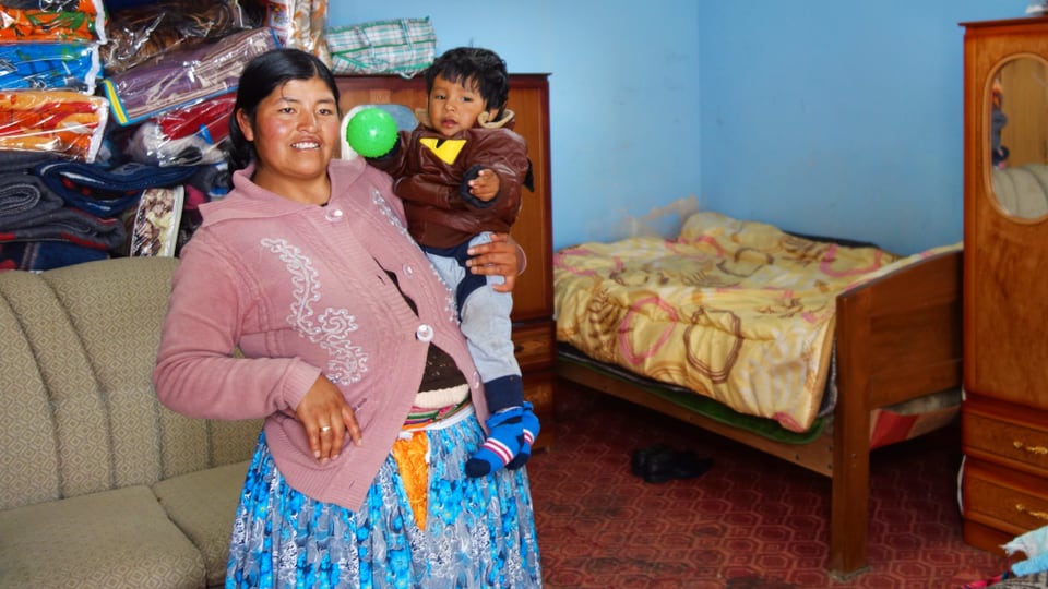 Eine bolivianische Frau trägt ihr Kleinkind auf dem Arm.
