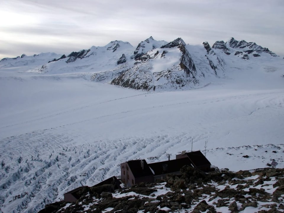 Berghütte oberhalb des Aletsch-Gletschers vor verschneiter Bergkette