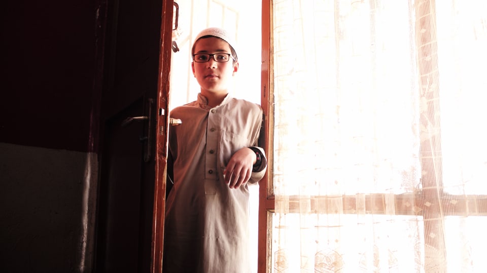 Junge mit Brille in einer Tür.