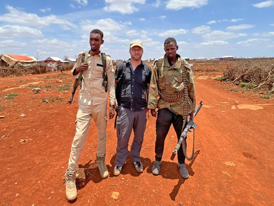Afrika-Korrespondent Samuel Burri steht in einem Dorf in Somalia, bewacht von zwei Soldaten.