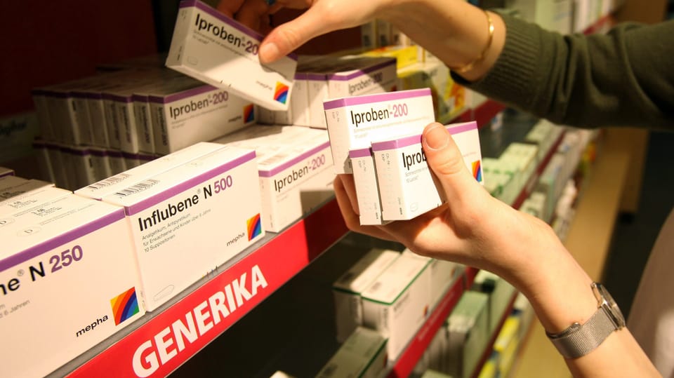 A person reaches for a generic drug from a shelf.
