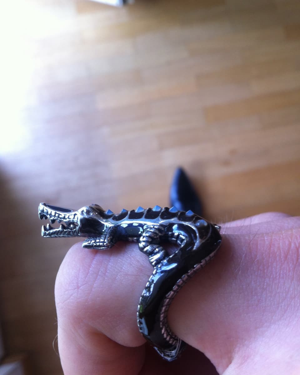 Nahaufnahme: ein geschwungener Ring mit einem grossen Krokodil an einem Finger.