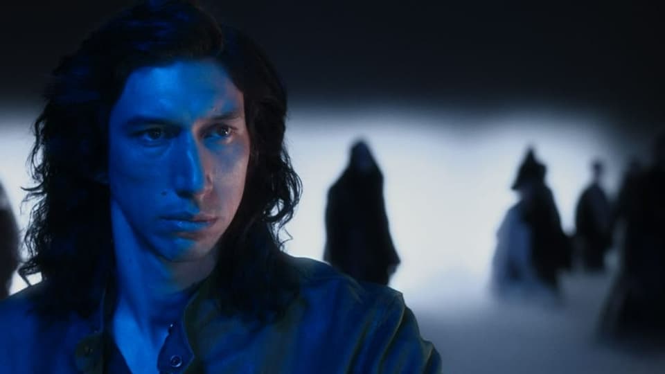 Ein Mann (Adam Driver) mit langen Haaren und finsterem Blick. Im Hintergrund schattenhafte Gestalten.